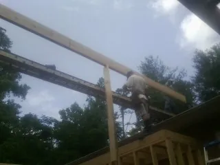 Carpenter setting a ridge beam over a new addition frame — Ice Dam Removal by Roofing Brothers in Buchtel