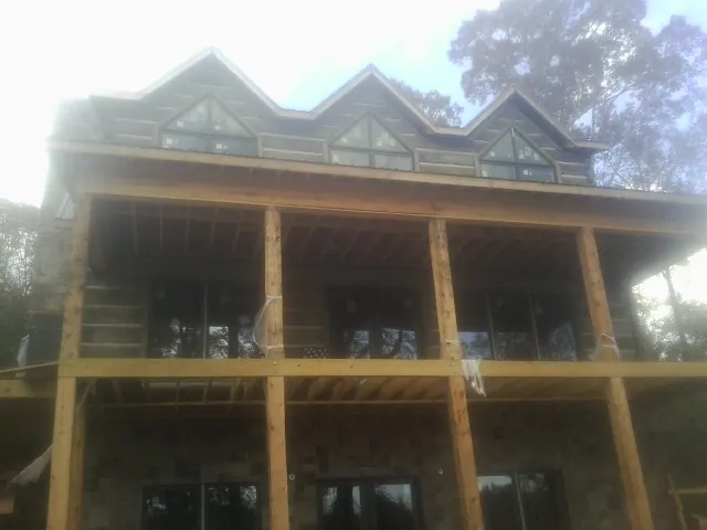 Dormers and porch framing on a large log home under construction — Roof Coating work by our crew in Buchtel