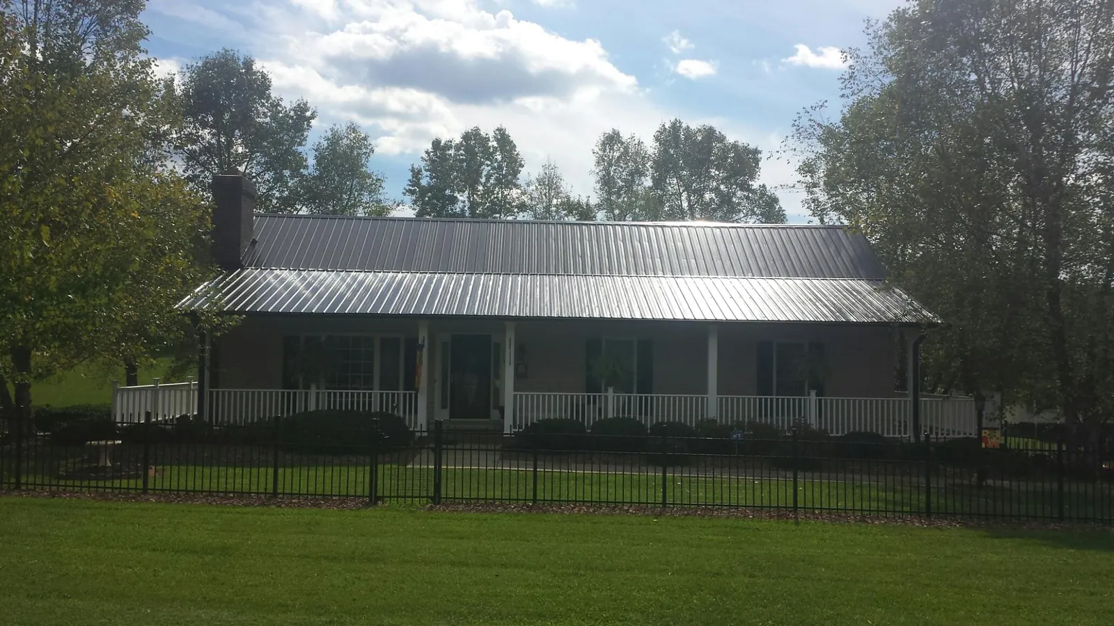 Gray metal roof on a brick ranch with a full width front porch — Gutter Guard Installation work by our crew in Buchtel