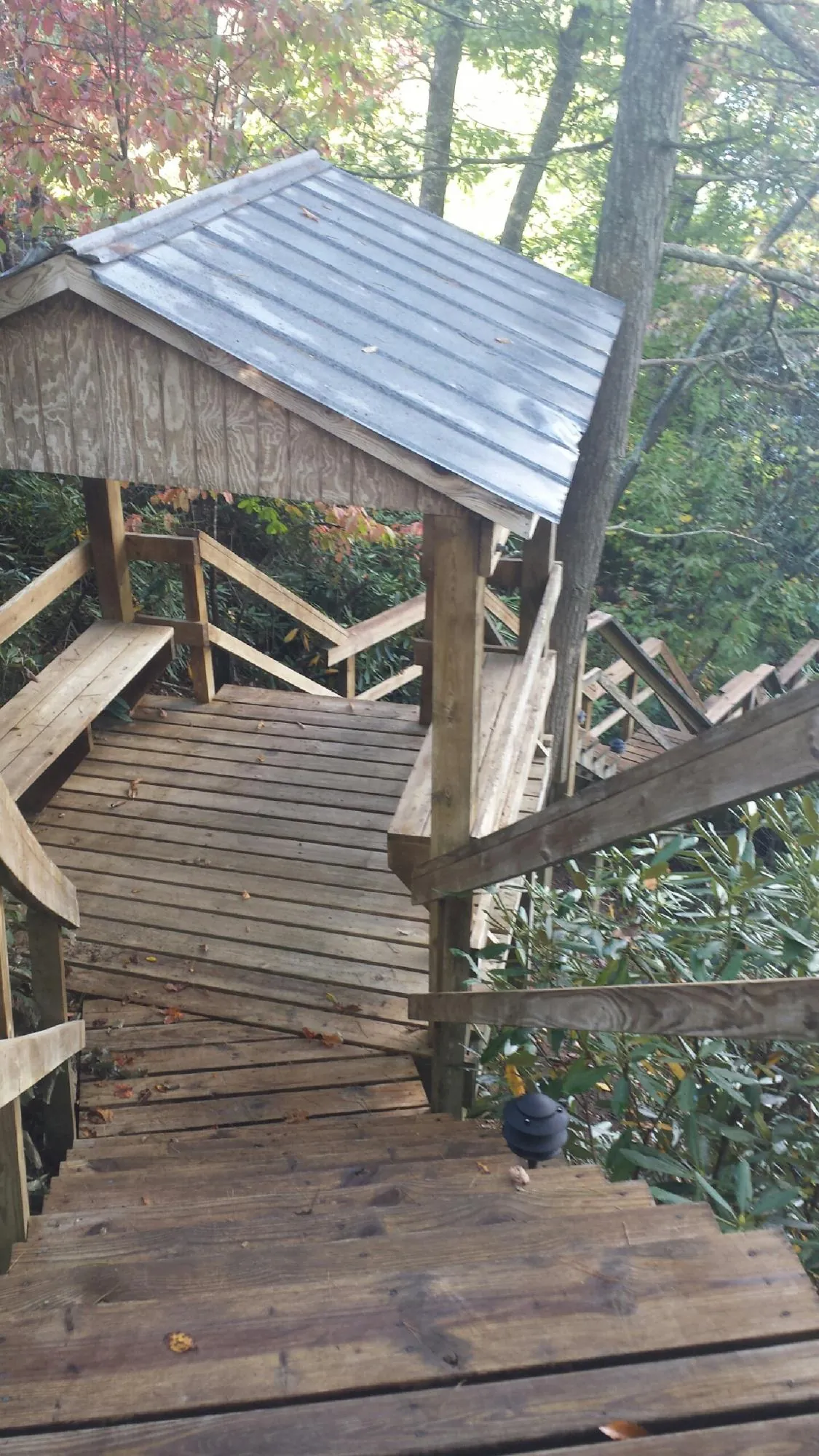 Metal roofed shelter over wooden steps on a wooded walkway — Skylight Repair & Installation work by our crew in Buchtel