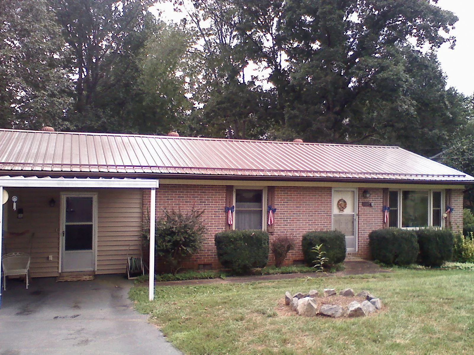 Bronze metal roof and carport on a brick ranch home — Roof Repair work by our crew in Buchtel