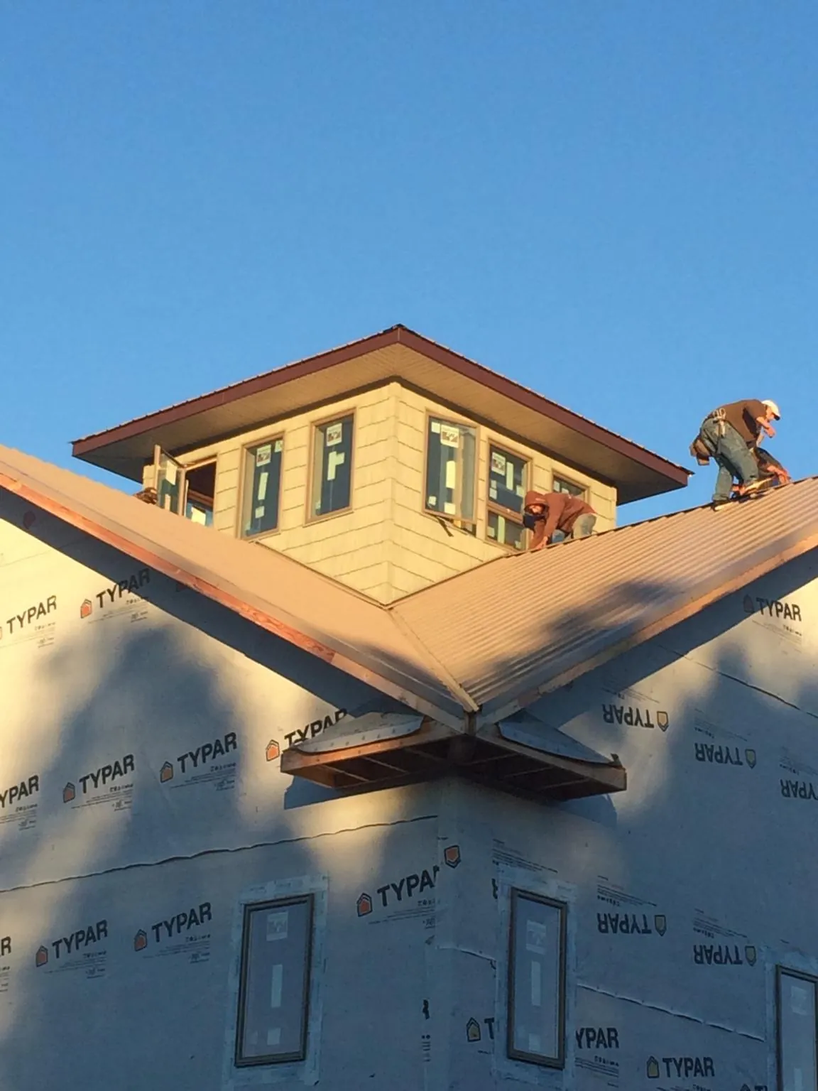 Roofers working around a rooftop cupola on a new metal roof at sunset — Roof Waterproofing in Buchtel by Roofing Brothers
